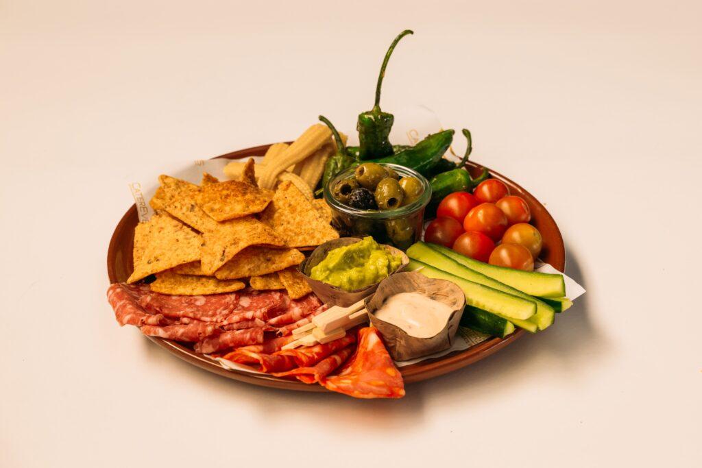 Tafelgarnituur Latin met nachochips, guacamole, chilidip, chorizo, pimientos de padrón en gemarineerde olijven