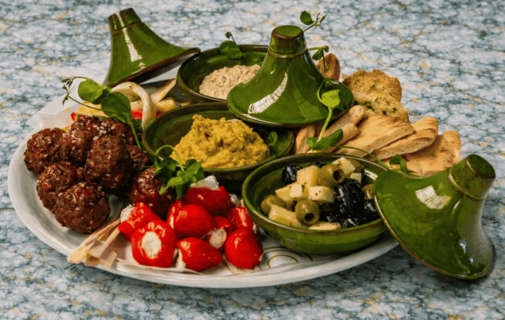 Tafelgarnituur Mezze met pita, hummus, baba ganoush, gegrilde groenten, olijven, feta en halal kipballetjes